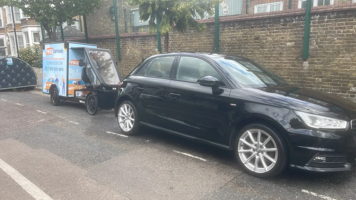 Yikes e-bike wash unit parked in a marked bay next to a black Audi A1 on a quiet residential street